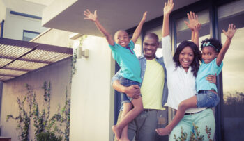 Happy,Family,Standing,In,The,Garden,Of,The,New,House